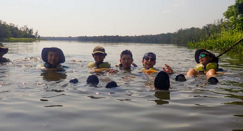 a group of teens swim while on a kayaking trip with outward bound